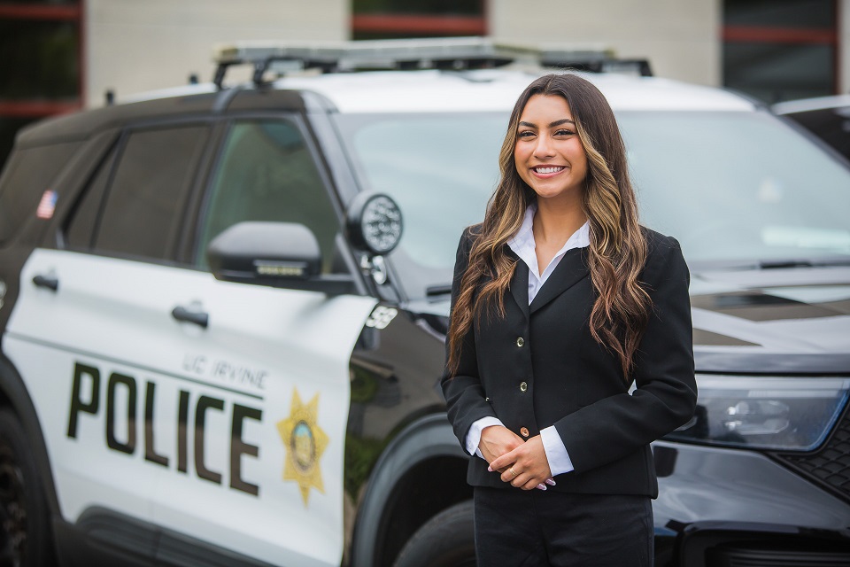 Intern smiles in front of the police car